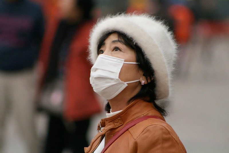 Figure 1. A woman in China wears a face mask to protect herself from air pollution. Photograph by Nicolò Lazzati, 2009. CC BY 2.0.