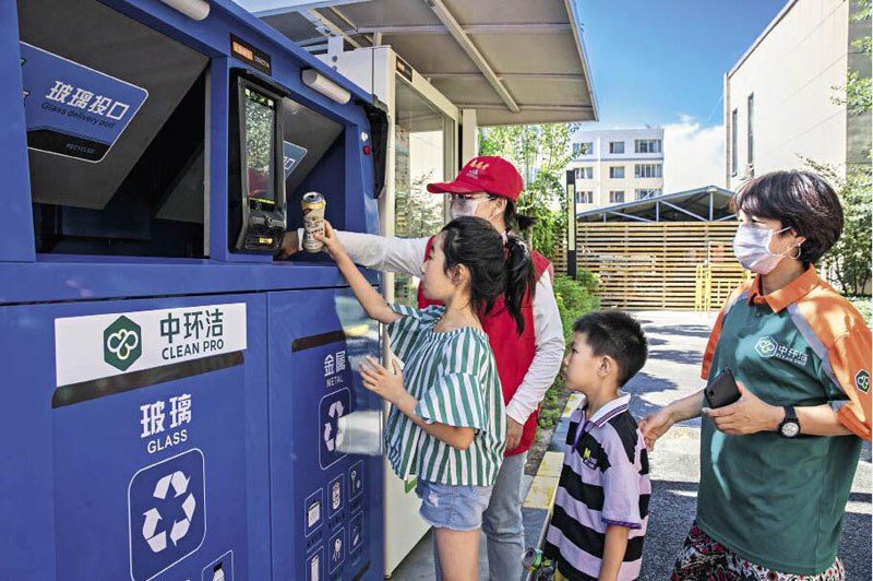 Le 4 août 2020, des volontaires du district de Yuquan, à Hohhot (Mongolie intérieure), apprennent aux enfants à utiliser des équipements intelligents de tri et de recyclage des déchets.