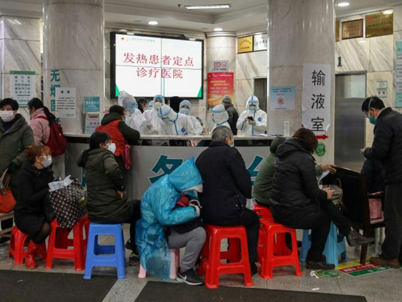 Des soignants en combinaison intégrale de protection reçoivent des personnes dans un centre médical, le 24 janvier 2020 à Wuhan, en Chine